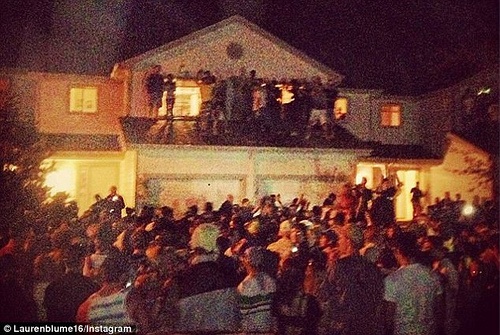 Large crowd gathered outside of a house at night