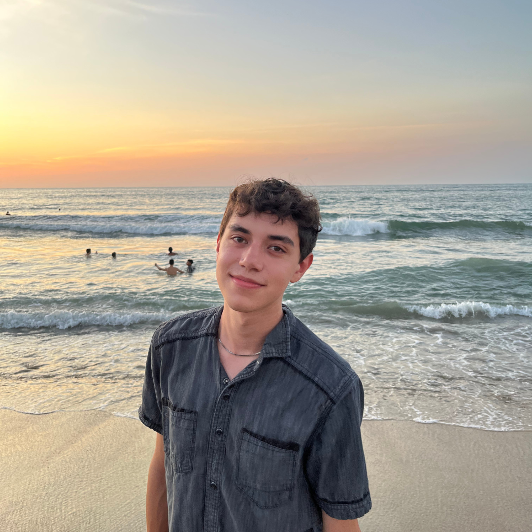 A student in front of the beach with a sunset 