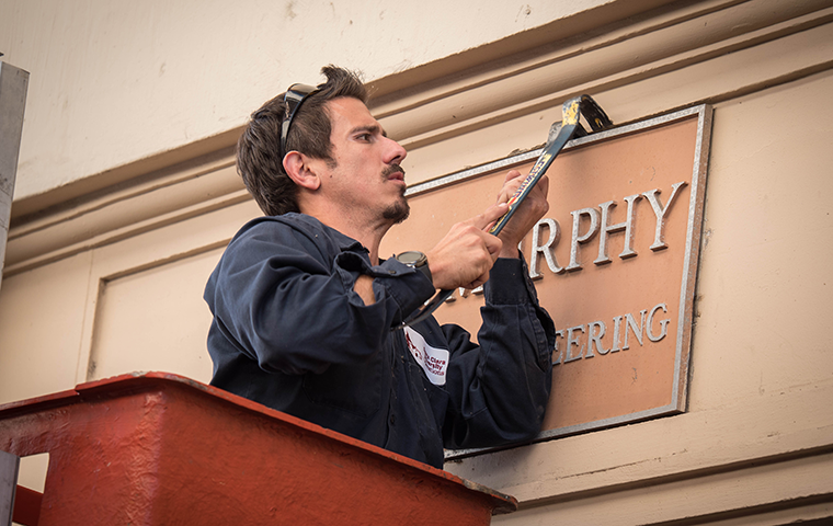 A University Operations employee removes a naming plaque on Bannan Hall during the move to Heafey Hall in December 2018. Photo by Charles Barry