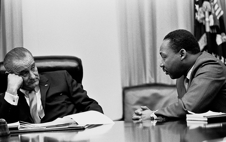 Lyndon Johnson and Martin Luther King sit at a table talking