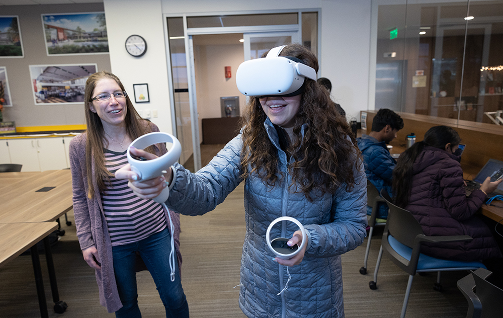 Julia Scott stands with Saint Francis student in VR helmet