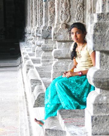 Photo of teen girl in India sitting next to temple