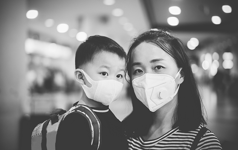 An asian mother and child wearing masks in an airport