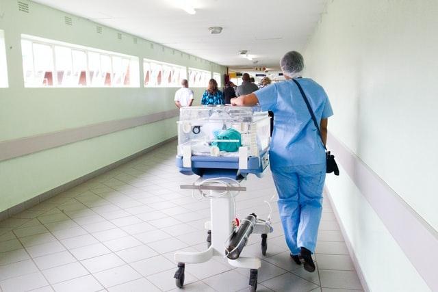 Photo of a hospital orderly walking down a hospital hallway.