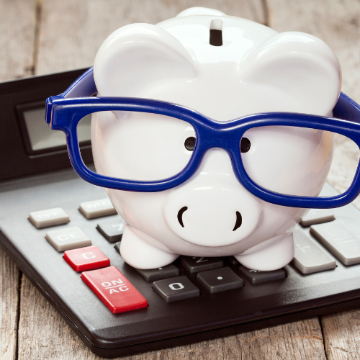 Photo of piggy bank wearing glasses on a calculator