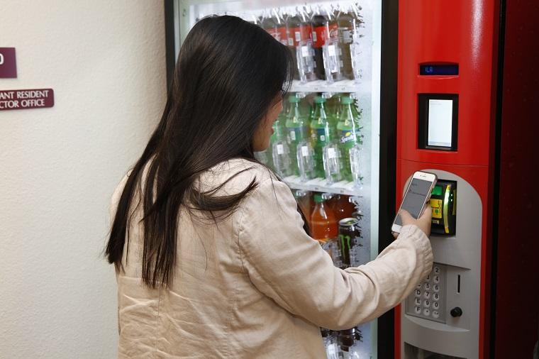 Woman using her digital ACCESS card to make a vending machine purchase.
