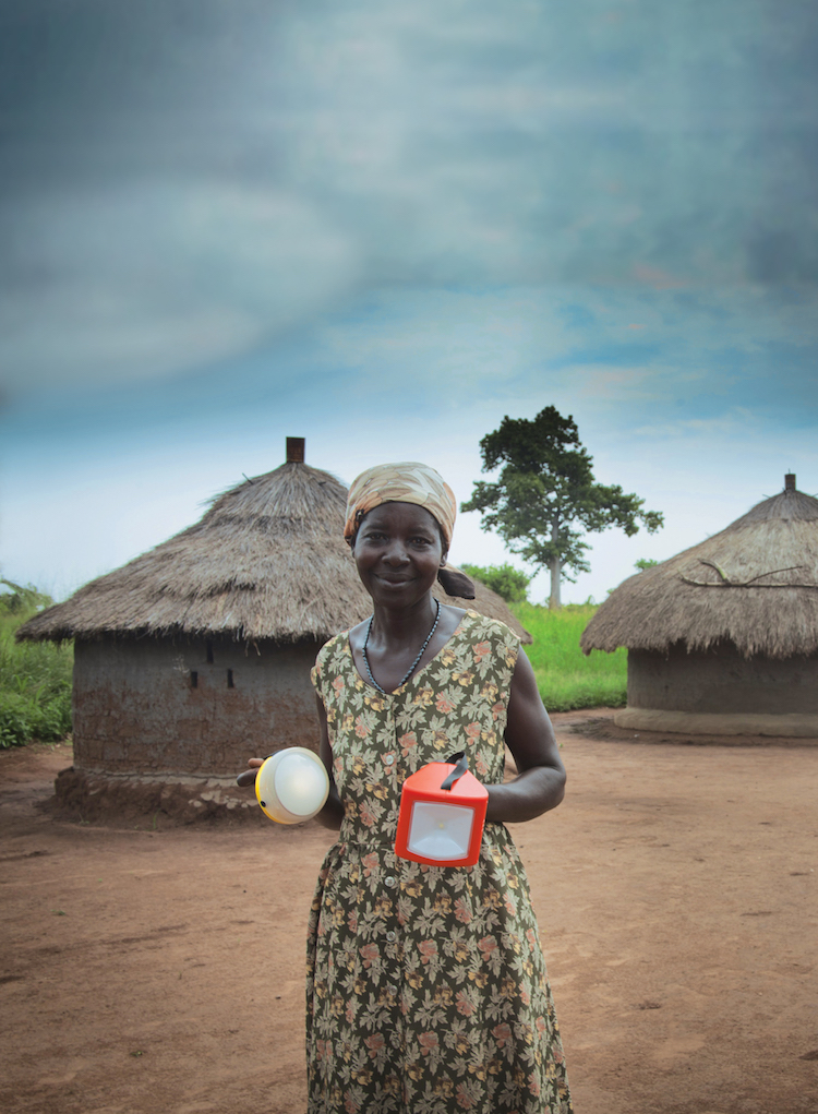 African woman holding two solar powered lamps