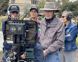 Four people standing behind a camera on a movie set.