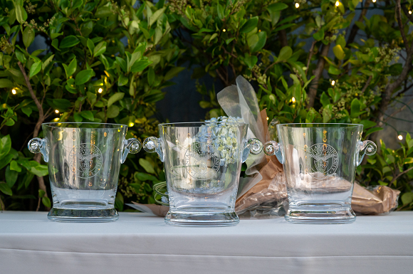 Three glass bowls sitting on a table with greenery behind.