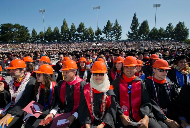Civil engineering students wear orange hard hats with their gowns instead of caps at undergraduate commencement