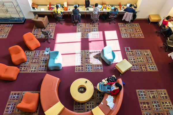 Students studying on the library's colorful lower level