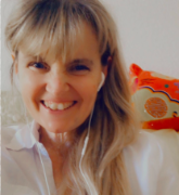 Smiling person with earbuds and a colorful pillow in the background.