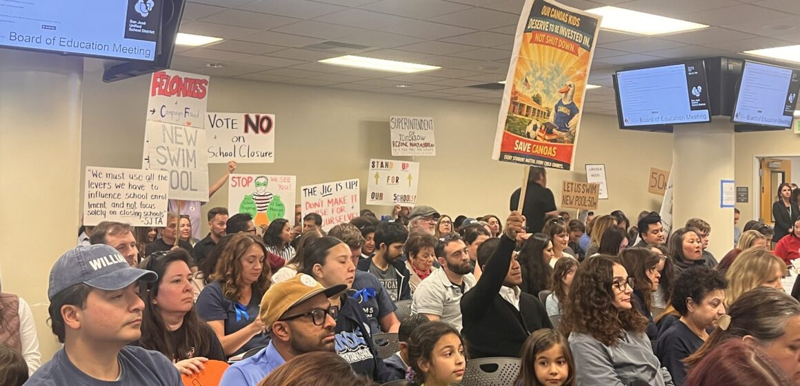 crowd sitting with protest signs
