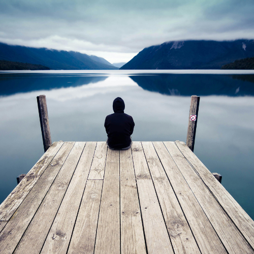 Person sitting on doc reflecting