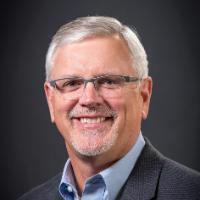 A man with glasses smiling, with the title Drew Starbird.