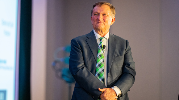 A man in a suit and tie looks off camera with a smile.