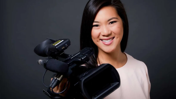 A smiling woman holding a film camera.