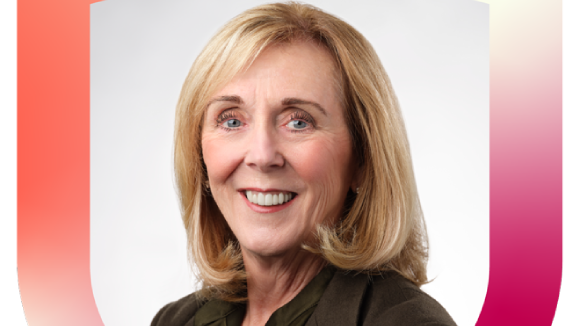 A smiling blond woman in a brown blouse and suit jacket.
