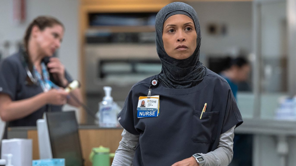 A still from the TV show The Pitt of the character Perlah, a nurse wearing scrubs and a hijab.
