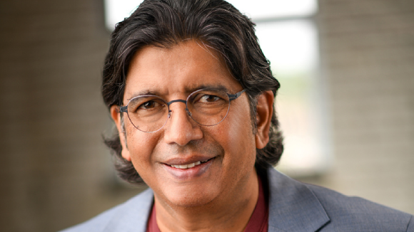 A smiling man in a suit jacket.