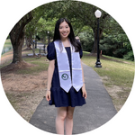 A person in a black dress with a graduation stole outdoors.