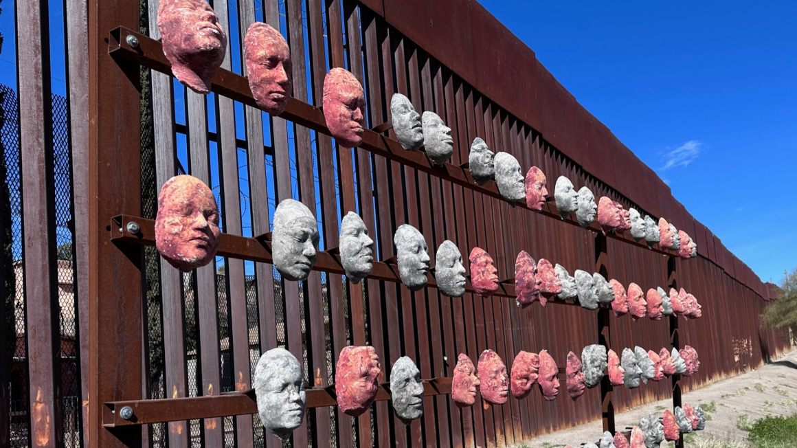 Wall of mask faces on US/Mexico border