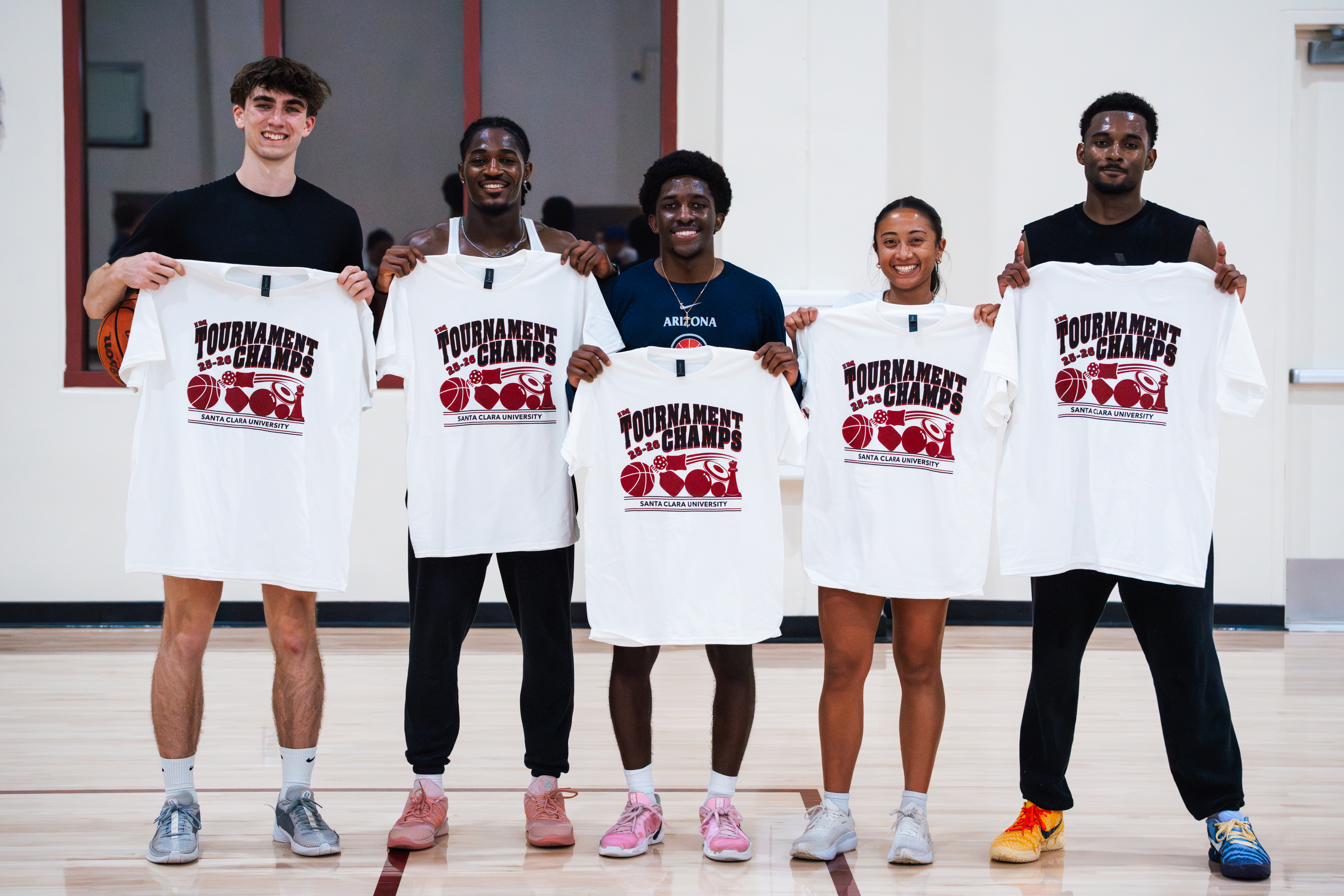Five hoopchella players holding up IM tournament shirts