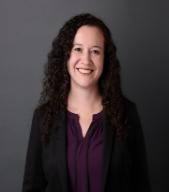 headshot of professor tania valdez a woman with curly brown hair in a purple shirt with a black blazer