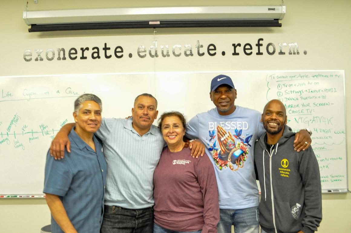 Group picture with four men and one woman smiling at camera