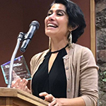 Photo of Farida Jhabvala Romero, labor correspondent for KQED, at a lectern with an award in her hand