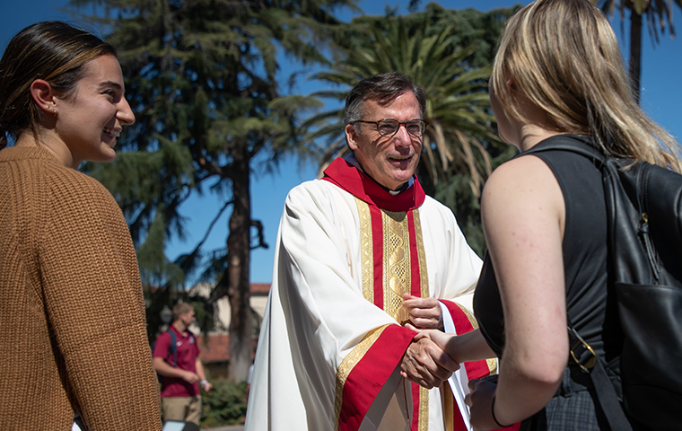 Fr. Kevin O'Brien shakes hands outside the Mission Church following the Mass of the Holy Spirit