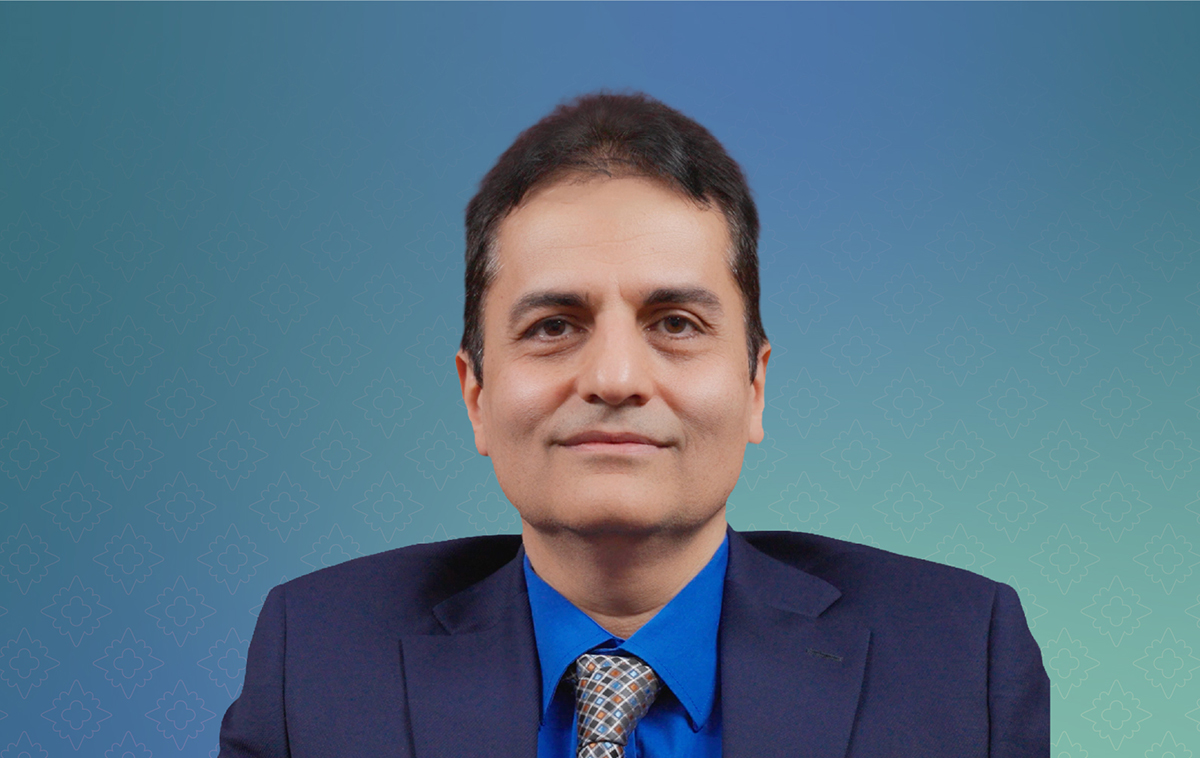 Hamed Akbari in suit in front of blue backdrop