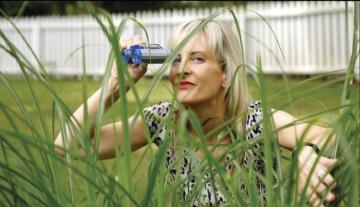 A woman looks through a magnifying device in a grassy yard. image link to story