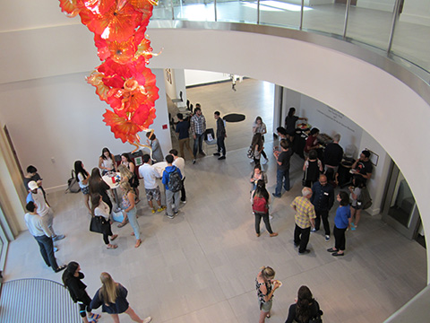 People walking in a curved, multi-story atrium with red art installation.