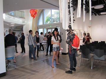 Students gathering in a hallway with chairs and a red balloon overhead.