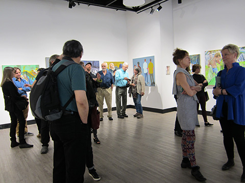People observing artwork in a gallery space with various paintings.