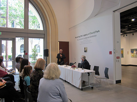 People attending a lecture in a room with arched windows.
