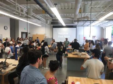 People gathering in a room, projector screen displaying content.