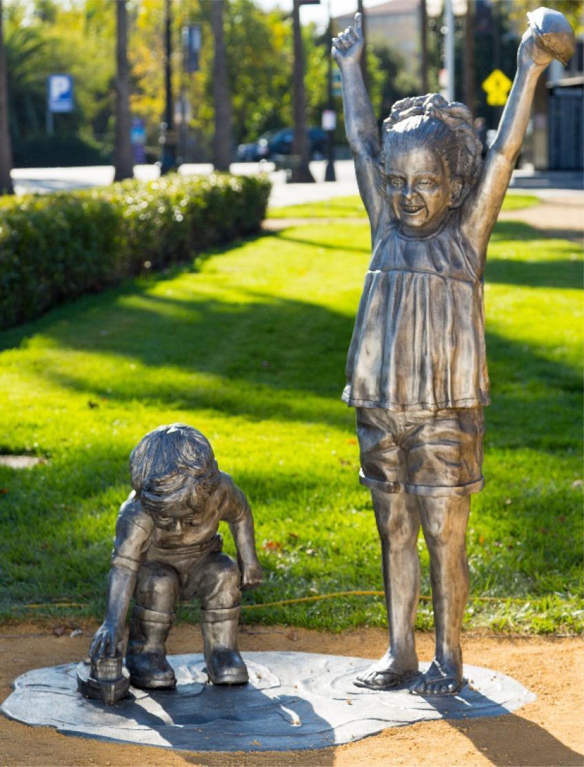 A metallic sculpture depicts two children playing. image link to story