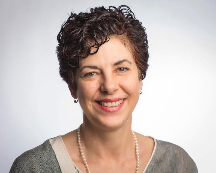 A person smiling with short hair against a white background. image link to story