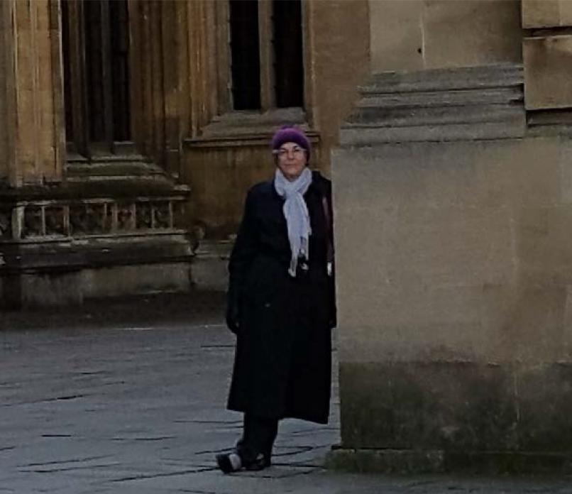 A person wearing formal academic attire stands in front of a historic building. image link to story