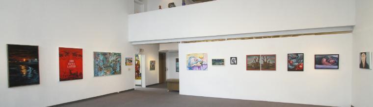 Art gallery with various paintings and photographs displayed on white walls.
