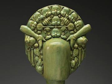 Green sculpture from Pancho Jimenez Exhibit featuring a bust with a detailed decorative headpiece. image link to story