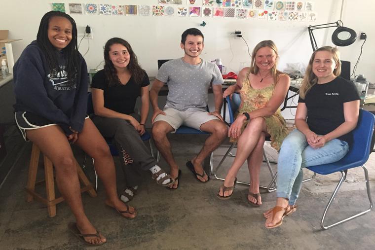 A group of five people sitting and smiling indoors. image link to story
