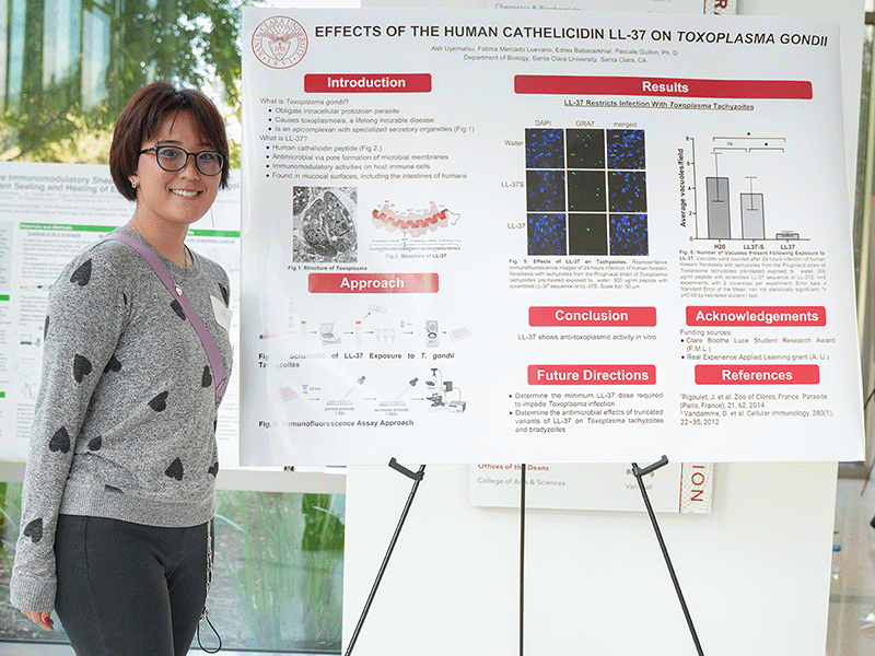 An SCU student stands next to her poster