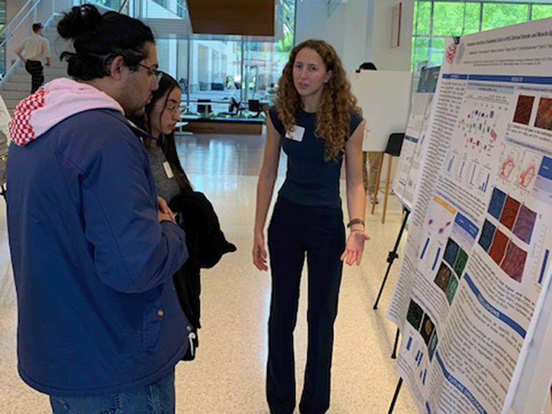 A student describes her research to two observers