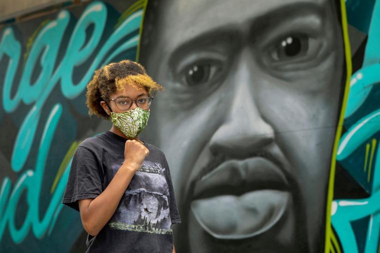 Jadyn Polk, 14, poses in front of a mural of George Floyd painted in downtown Oakland, Calif., Friday, June 5, 2020. Polk is the daughter of activist Cat Brooks and she participated in the peaceful student-led march of 15,000 people from Oakland Technical High School to City Hall. (Karl Mondon, Bay Area News Group)