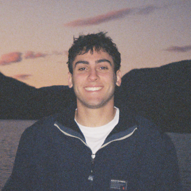 A photo of Lucas smiling with sunset in the background