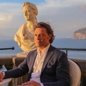 Man in a suit with the Amalfi Coast backdrop at sunset.