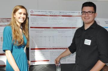 Two students presenting research in front of a poster.